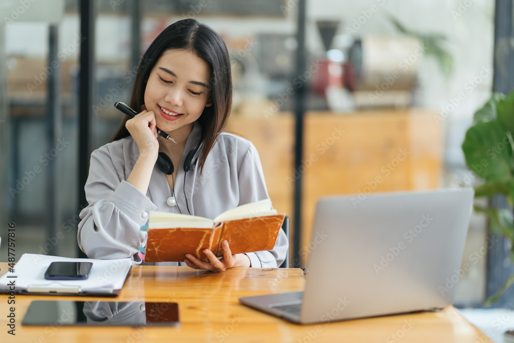 年轻的亚洲女性在日记中记笔记。女大学生在为考试做笔记