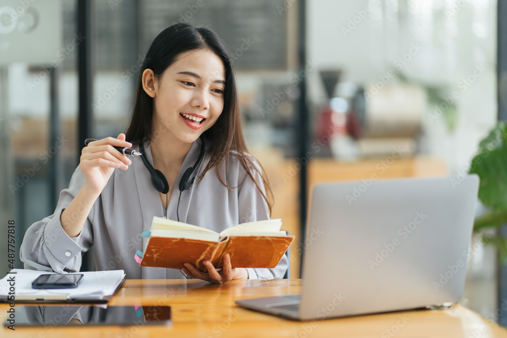 漂亮的年轻自由职业女性坐在咖啡桌旁用笔记本电脑。快乐的微笑女孩Wor