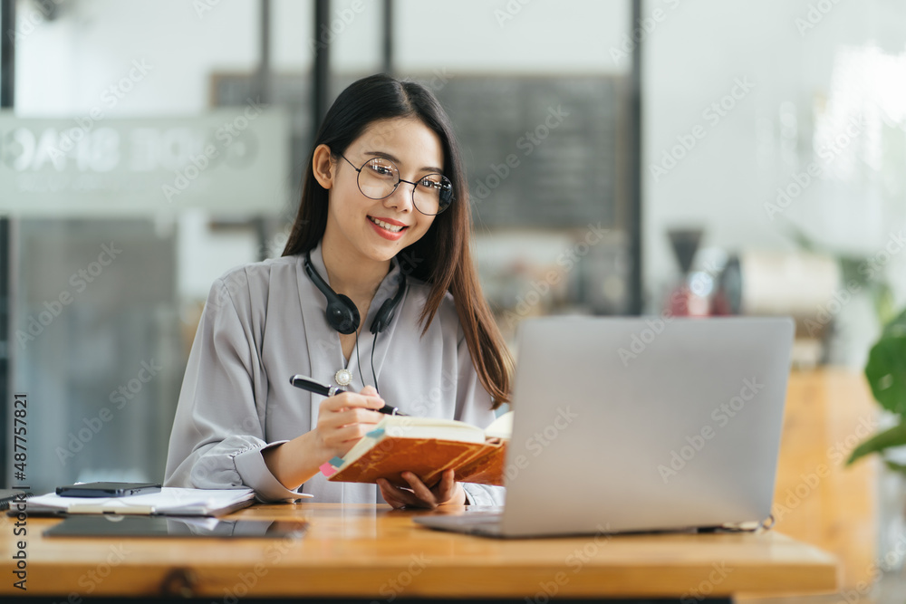 漂亮的年轻自由职业女性坐在咖啡桌旁用笔记本电脑。快乐的微笑女孩Wor