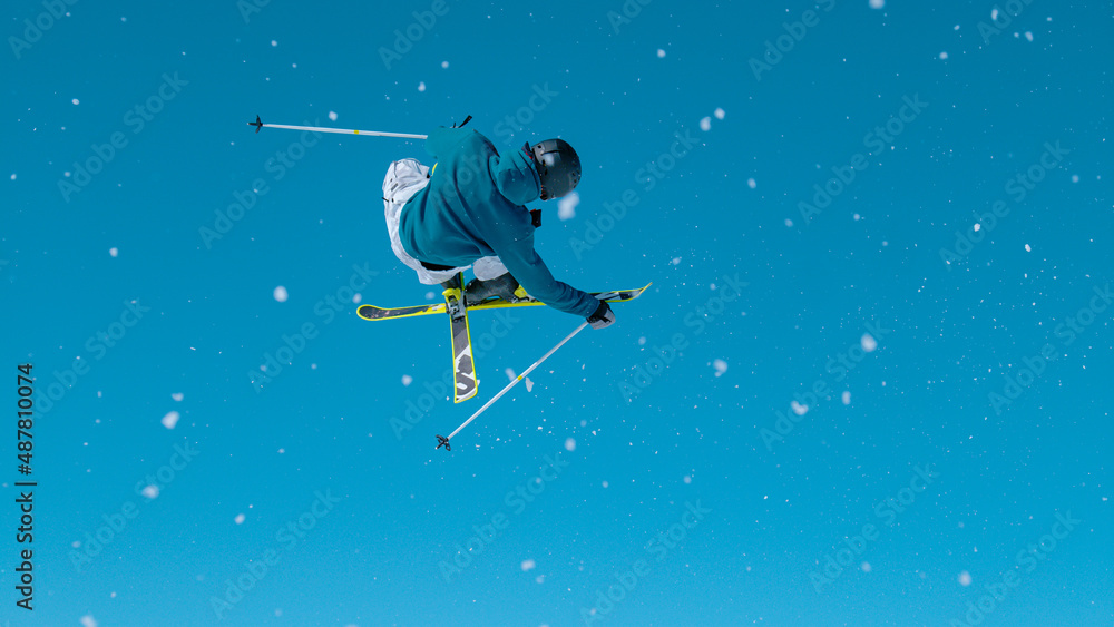 Action shot of a male skier jumping off a kicker and doing a high-flying trick.