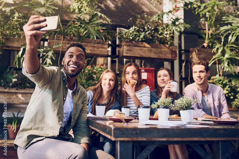 Lunchtime selfie with my besties. Shot of a young man taking a selfie while out with friends at a ca