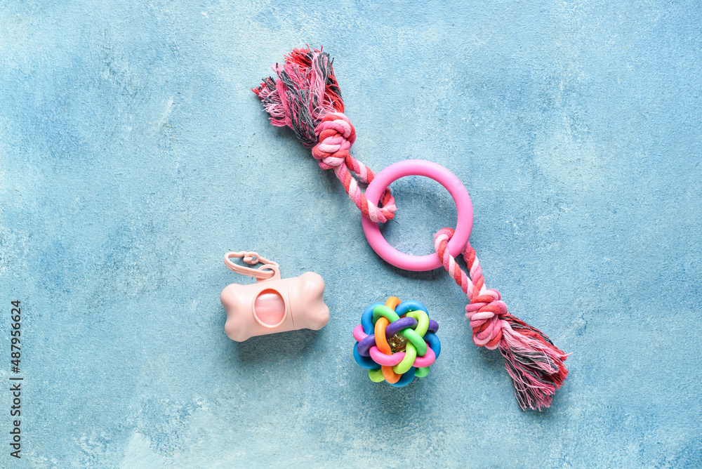 Dispenser with pet waste bags and toys on blue background