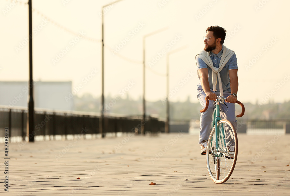 Handsome bearded man riding bicycle on embankment