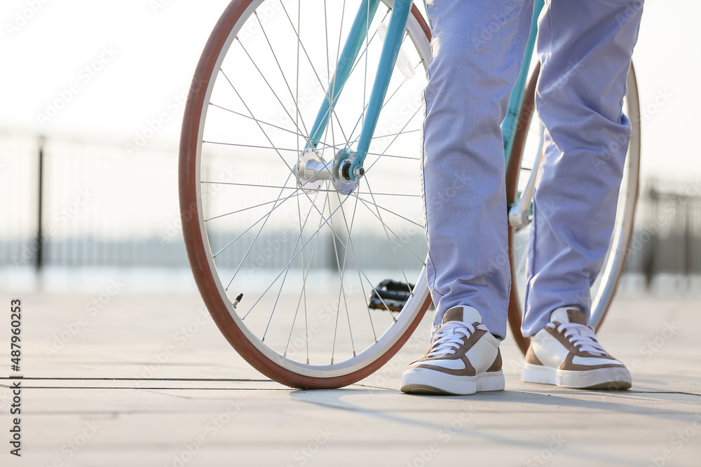 Young man with bicycle on embankment, closeup