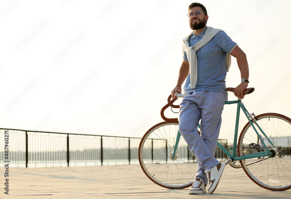 Young bearded man with bicycle on embankment