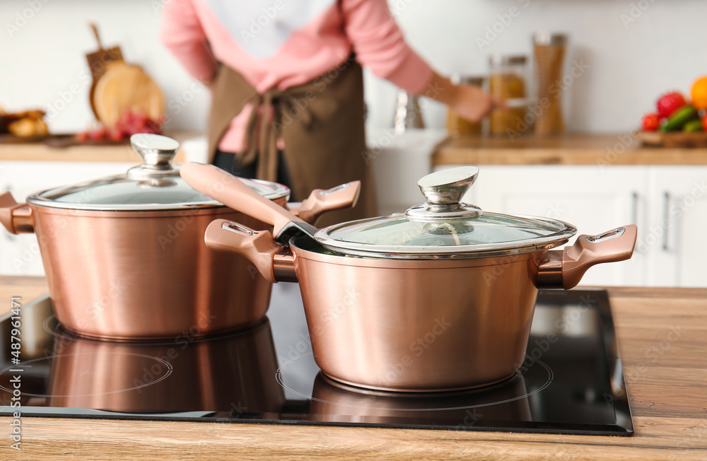 Shiny copper cooking pots on stove in kitchen, closeup