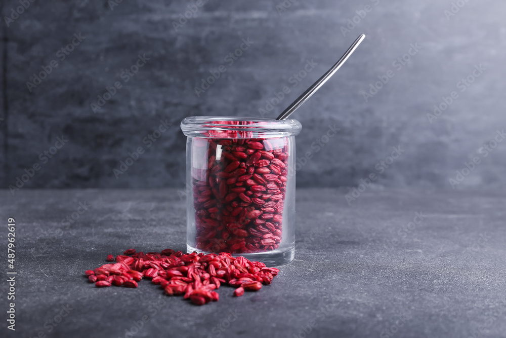 Jar with dried barberries on dark background