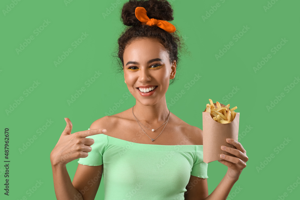 Young African-American woman with french fries on green background