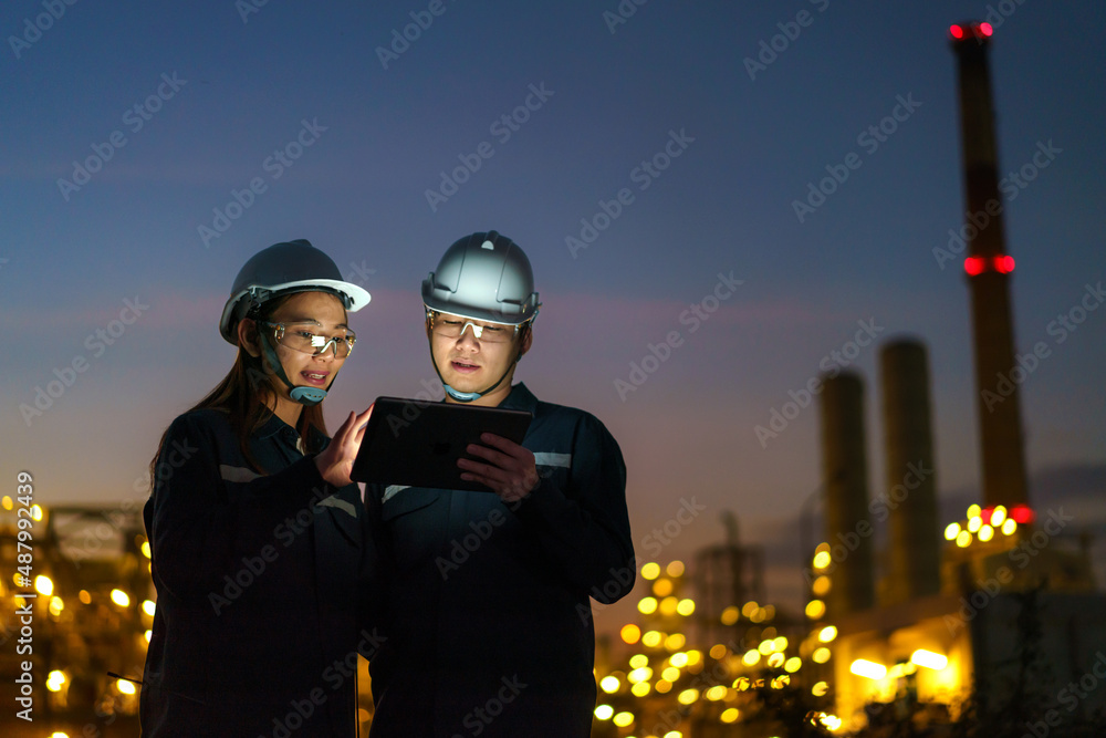 亚洲工程师，男男女女，正在通过查看炼油厂的夜间维护情况