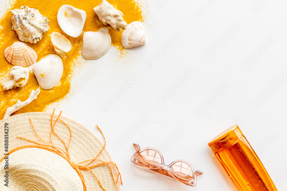 Beach sand and seashells with straw hat and bottles od sunscreen