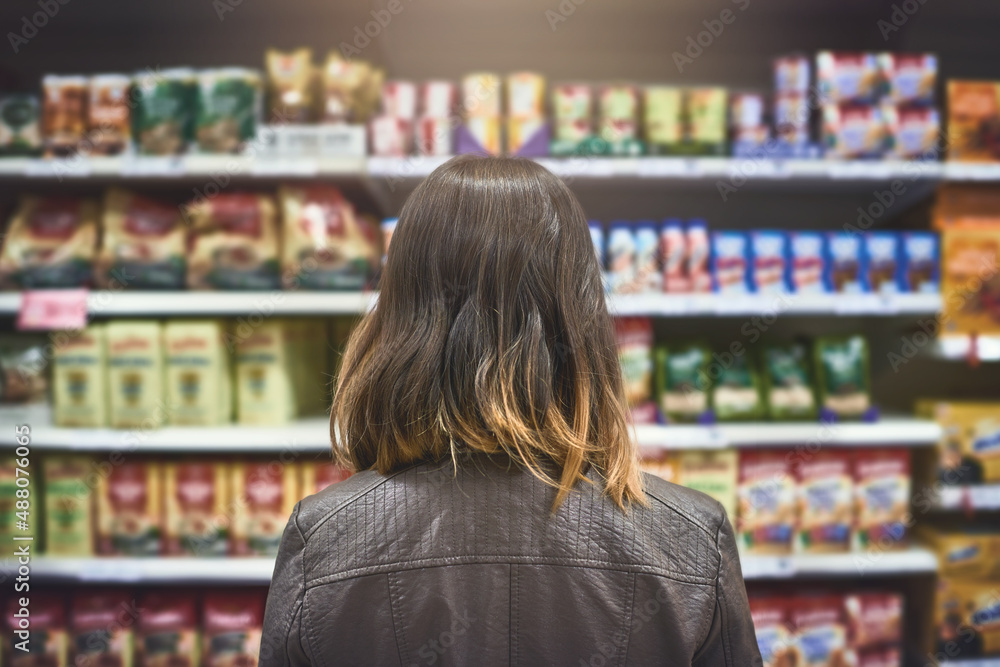 这么多品牌……一名年轻女子在杂货店购物的后视镜头。