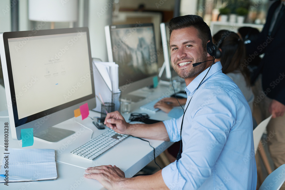 Putting a positive spin on his calls. Portrait of a happy and confident young man working in a call 