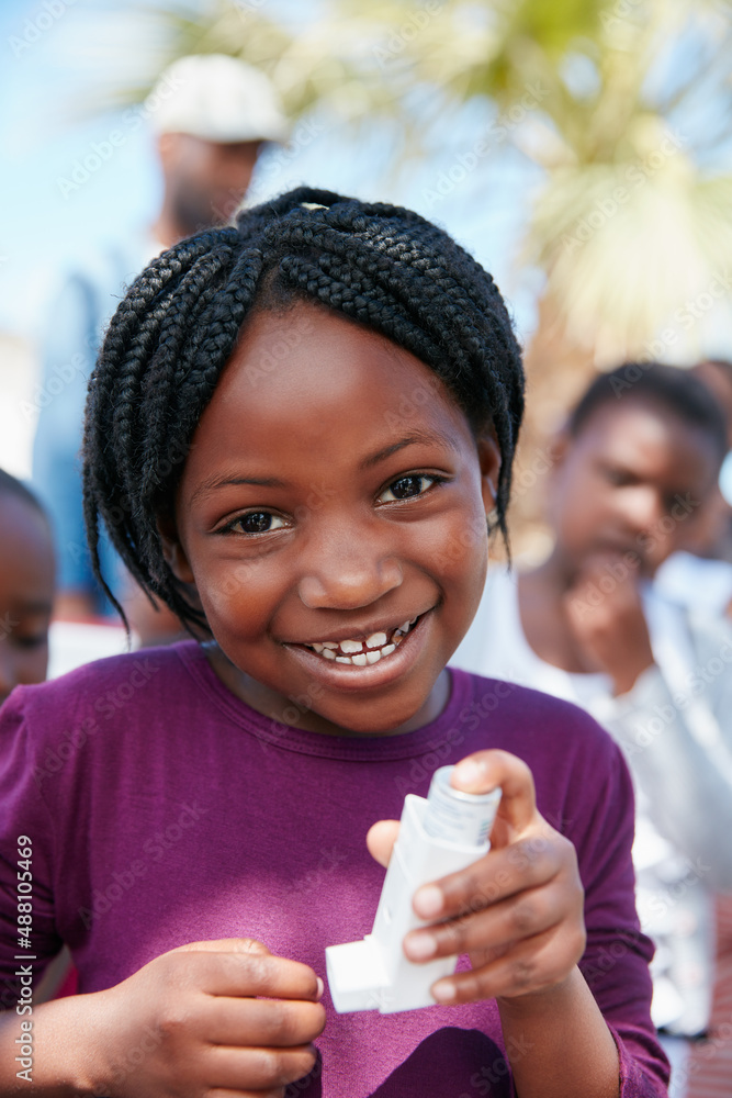 I can breathe easy now. Portrait of a little girl holding an asthma inhaler at a community outreach 