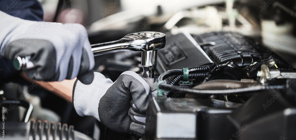 Professional mechanic working on the engine of the car in the garage. Car repair service.