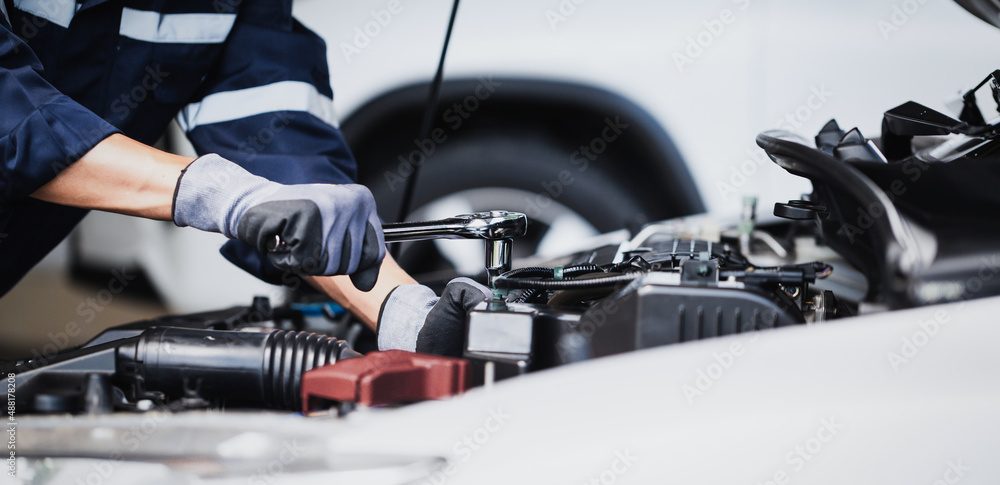 Professional mechanic working on the engine of the car in the garage. Car repair service.