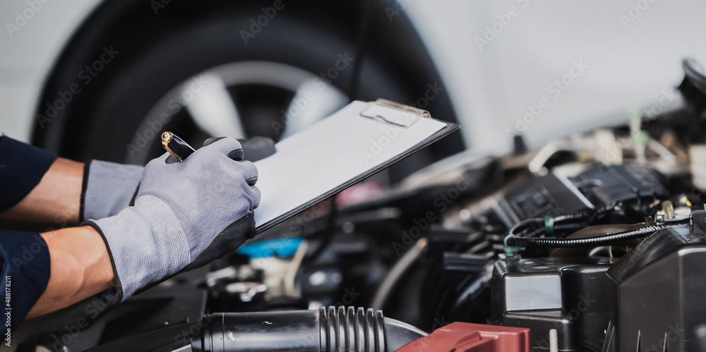 Professional mechanic working on the engine of the car in the garage. Car repair service.