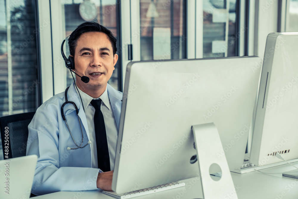 Doctor wearing headset talking actively on video call in a clinic or hospital . Concept of telehealt