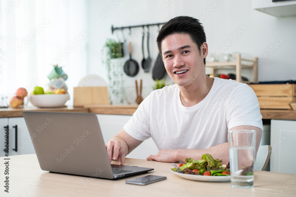 Portrait of Asian business man eat healthy salad while work from home. 