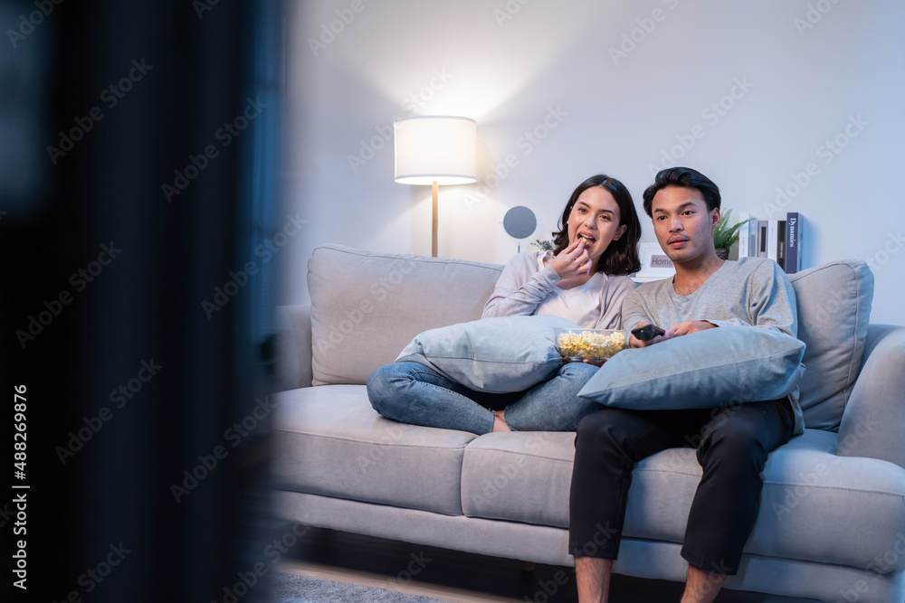 Asian loving young couple watch movie together in living room at home. 