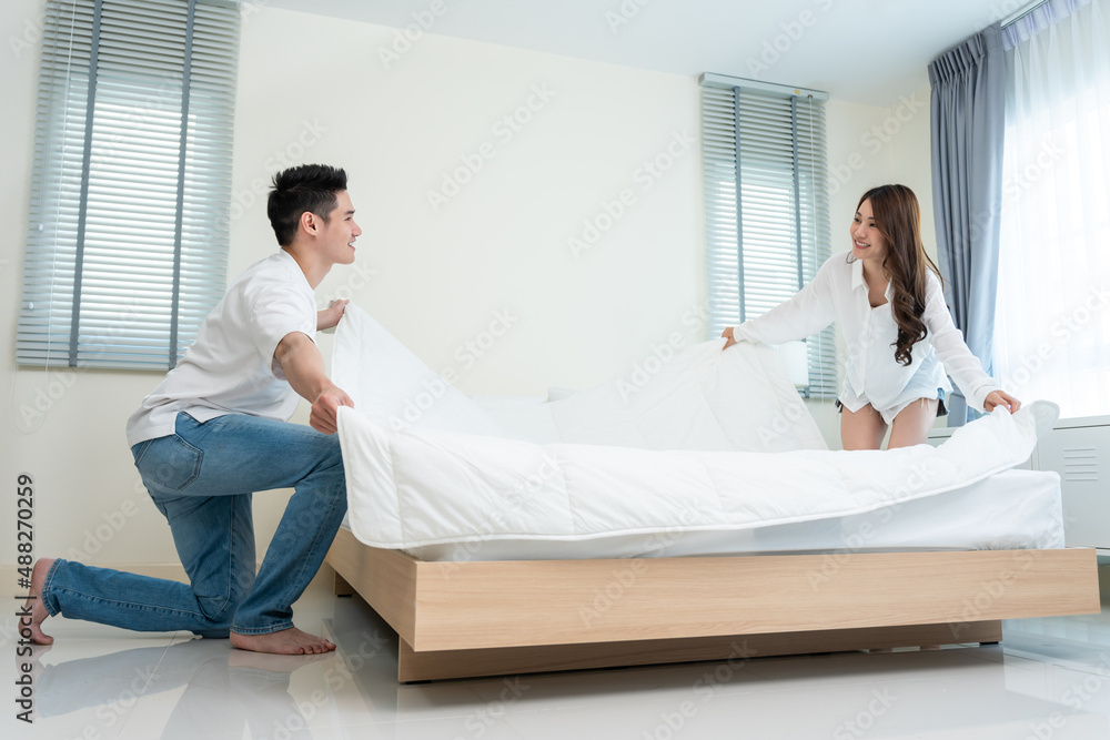 Asian young couple folding blanket after wake up together in morning. 