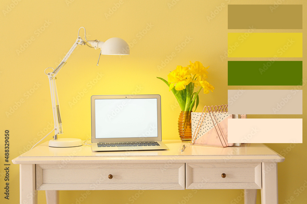 Modern workplace with modern computer and narcissus flowers in room. Different color samples