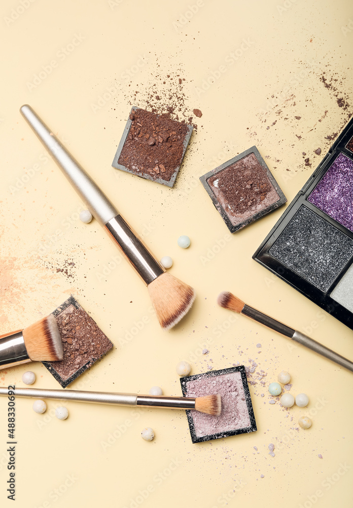 Makeup brushes and eye shadow palettes on light background