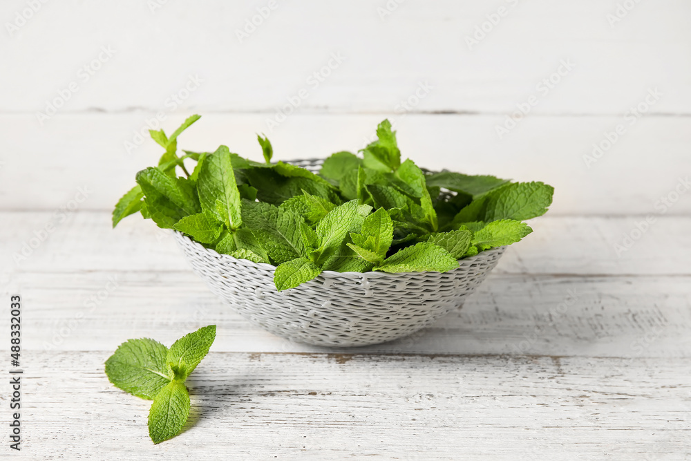 Wicker bowl with mint leaves on wooden background