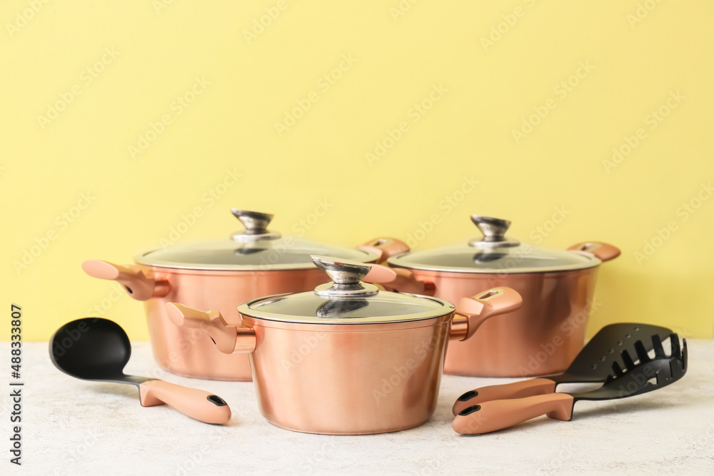 Different kitchen utensils on table near color wall