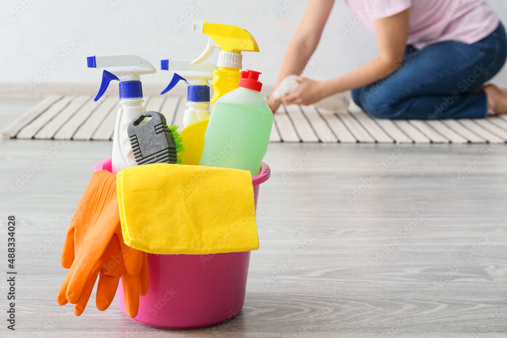 Bucket with cleaning supplies on wooden floor