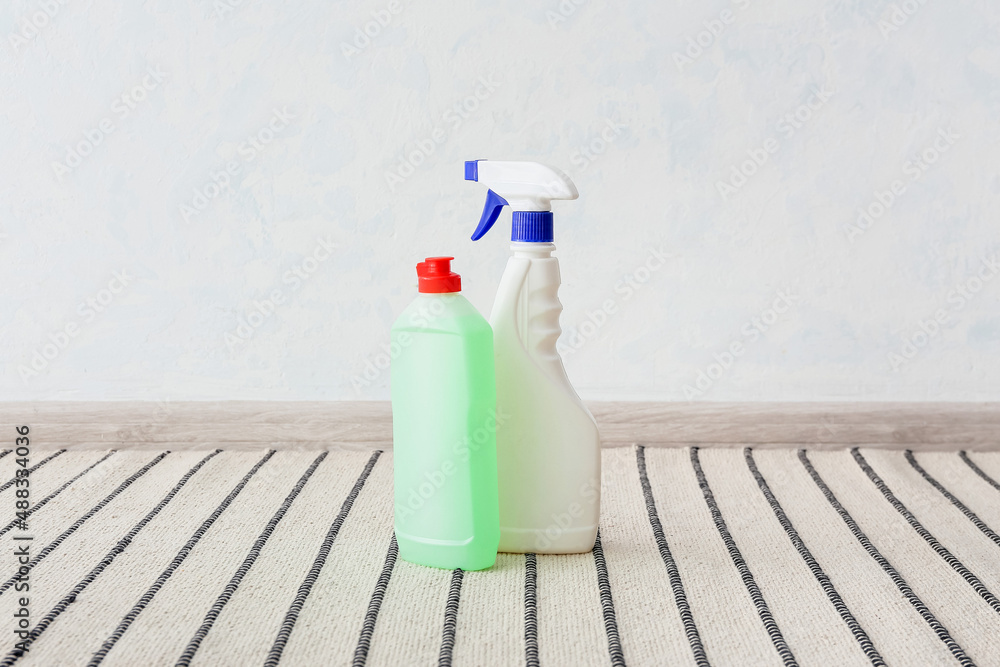 Bottle of detergent on striped carpet near light wall