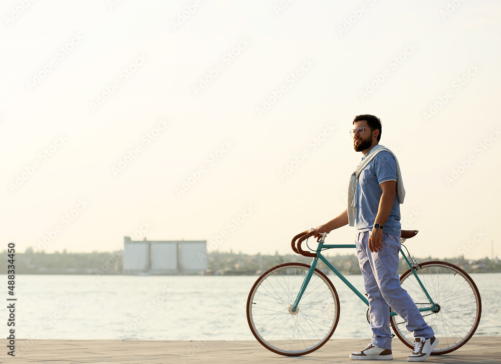 Young bearded man with bicycle near river