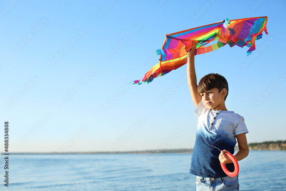 Cute little boy with kite near river