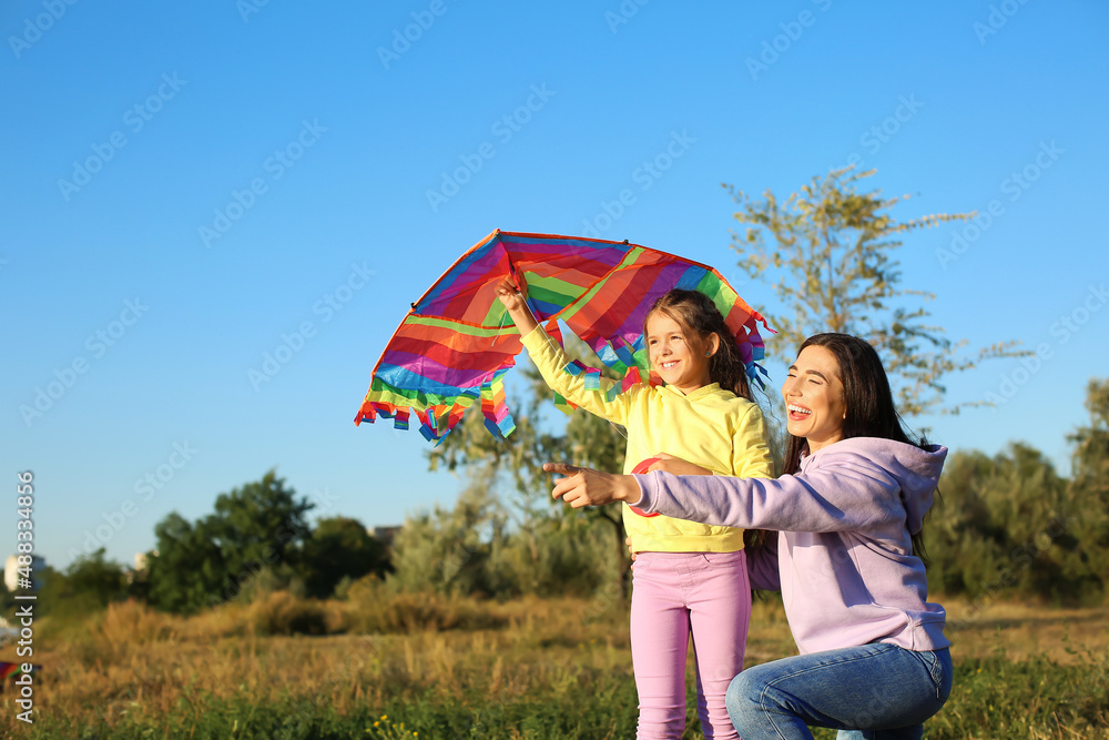 Cute little girl with kite and her mother pointing at something outdoors