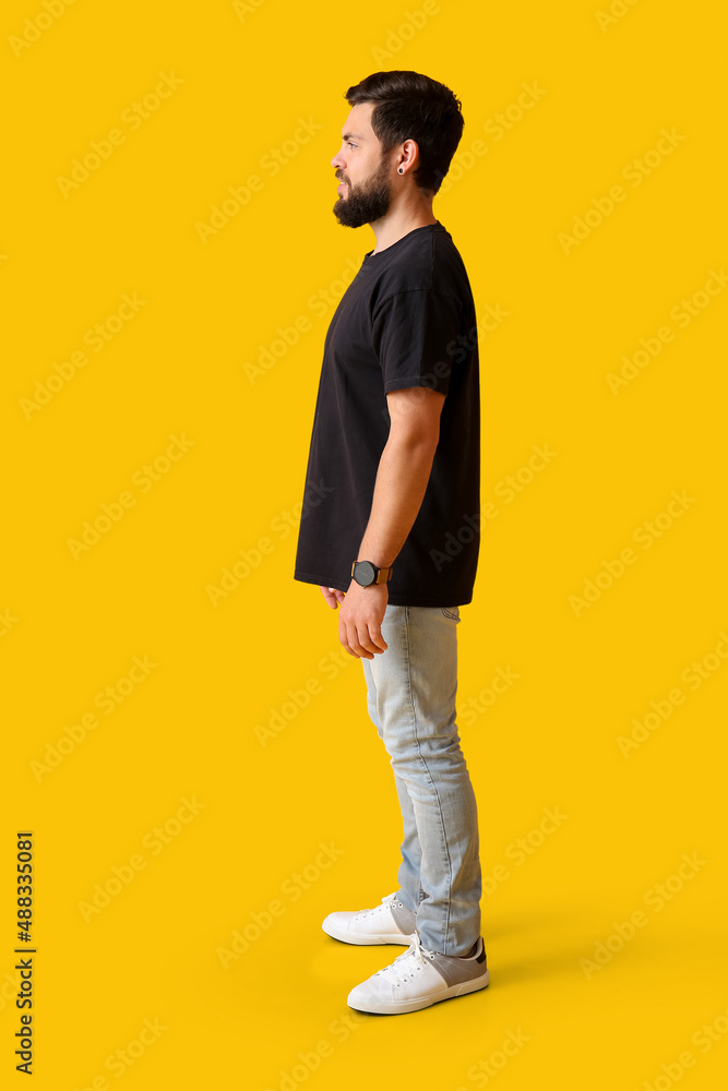 Handsome man in black t-shirt on yellow background