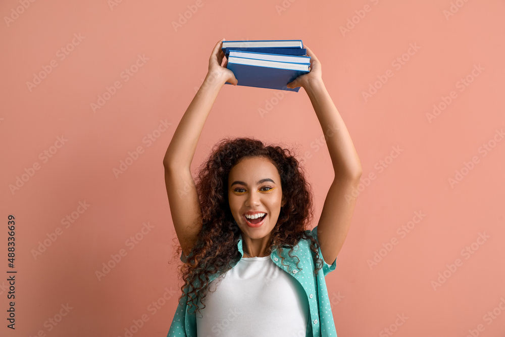 Beautiful young African-American woman with books on color background