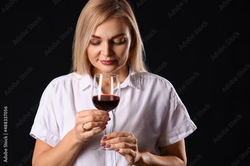 Female sommelier tasting wine on dark background