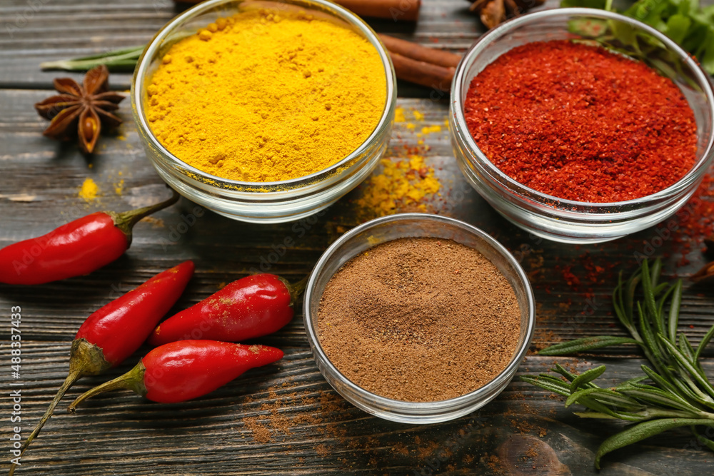 Composition with bowls of aromatic spices on dark wooden background, closeup