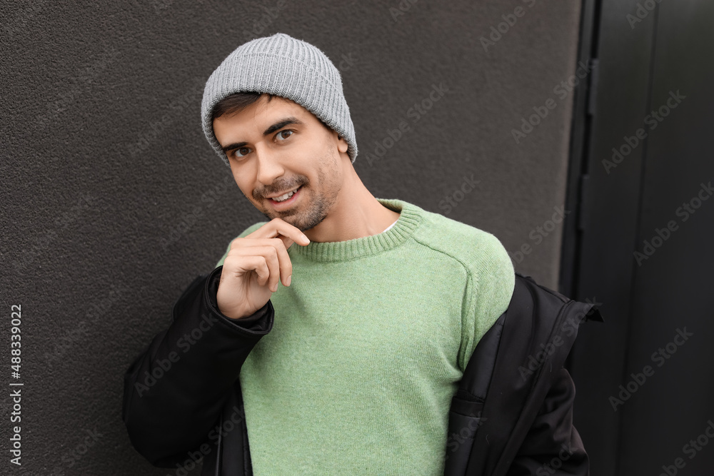 Handsome young man in knitted sweater on dark background