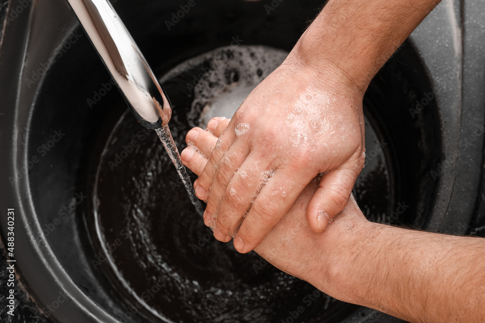 Man washing hands with soap in black sink, closeup