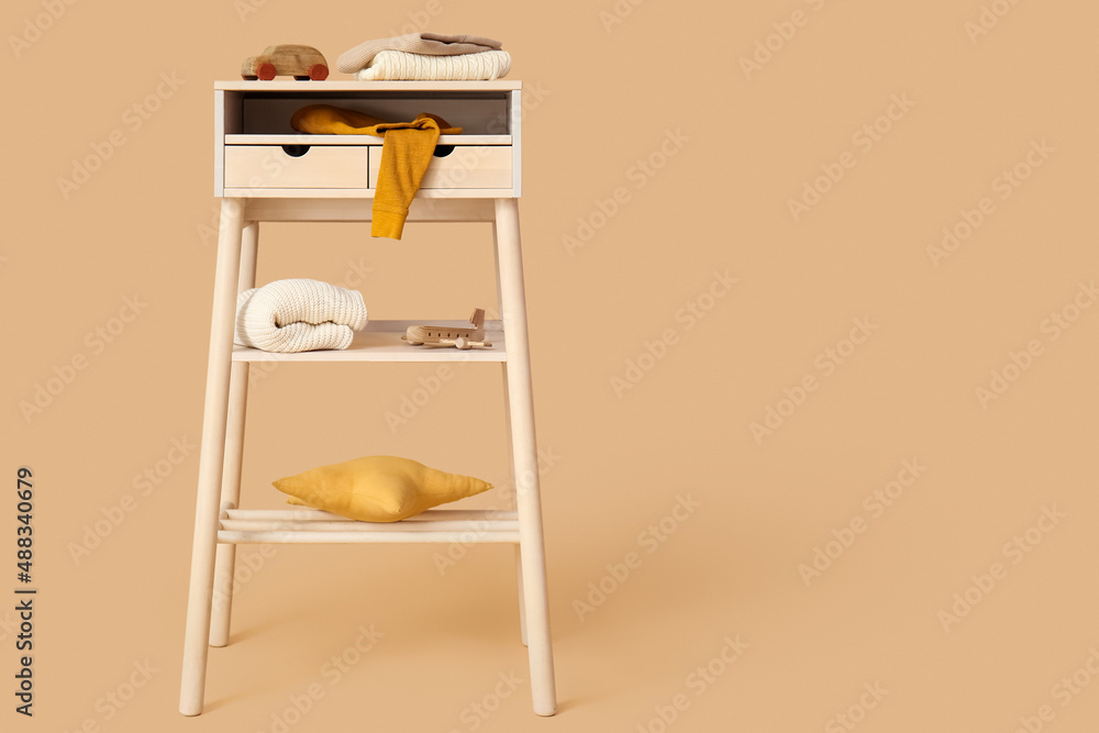 Standing desk with stylish childrens sweaters and toys on color background