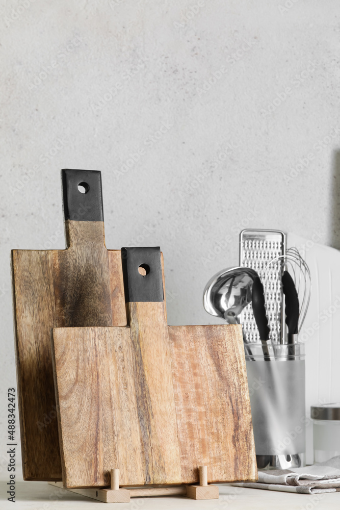 Wooden cutting boards and kitchen utensils on light background