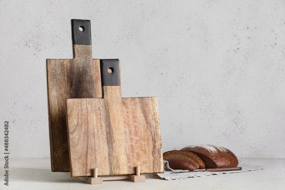 Wooden cutting boards and bread on light background