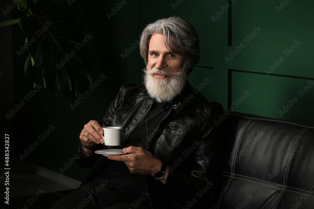 Handsome mature bearded man drinking coffee at home