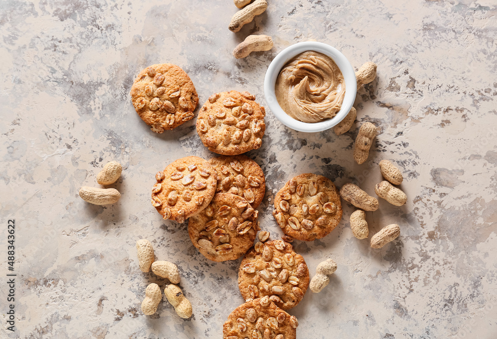 Tasty peanut cookies and butter on beige background