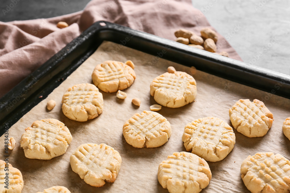 Baking sheet with tasty peanut cookies on table, closeup