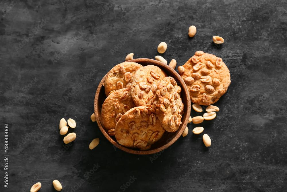 Bowl with tasty peanut cookies on black background