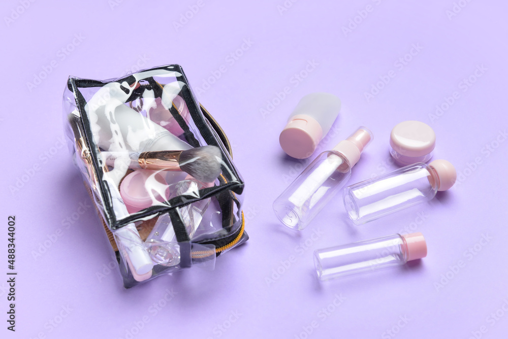 Empty travel bottles and bag with cosmetics on lilac background