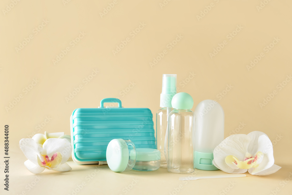 Composition with empty travel bottles and flowers on color background