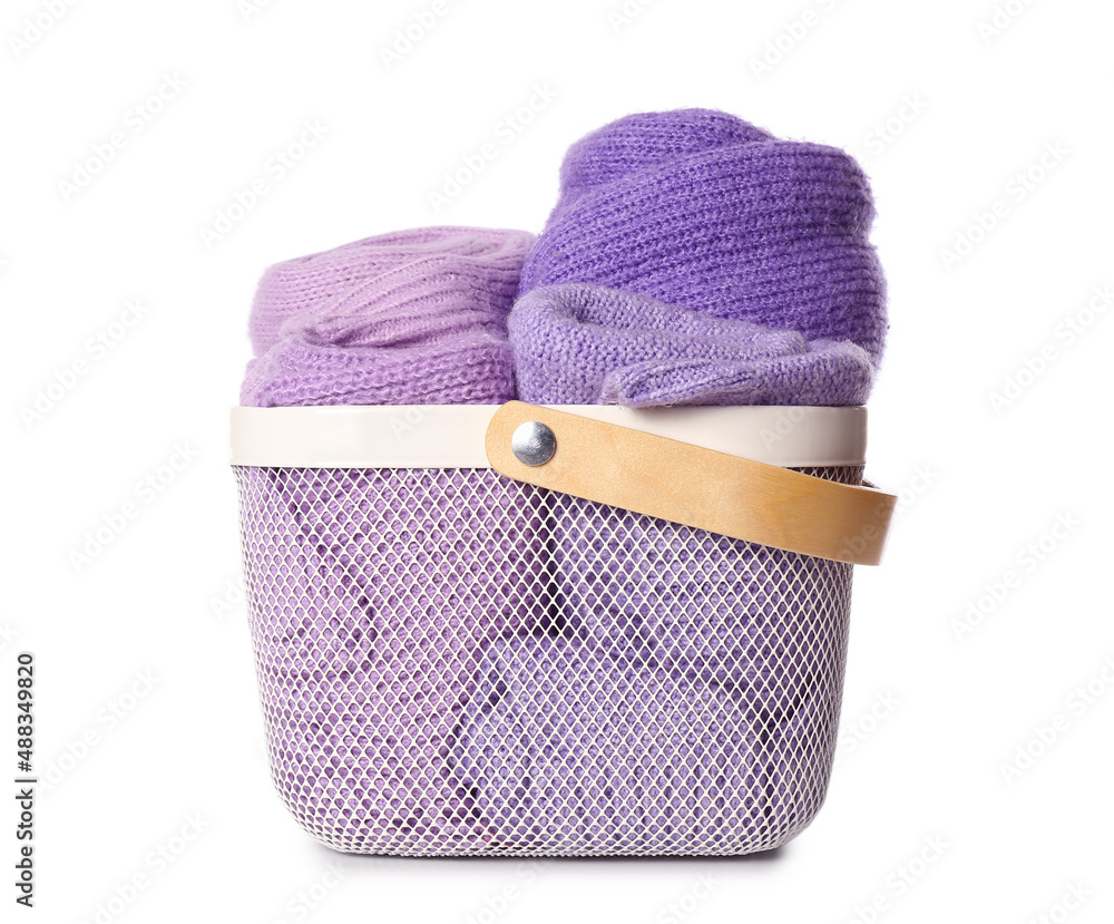 Basket with folded lilac sweaters on white background