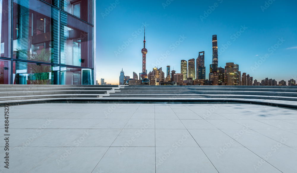 Panoramic skyline and modern commercial buildings with empty square floor in Shanghai at night, Chin